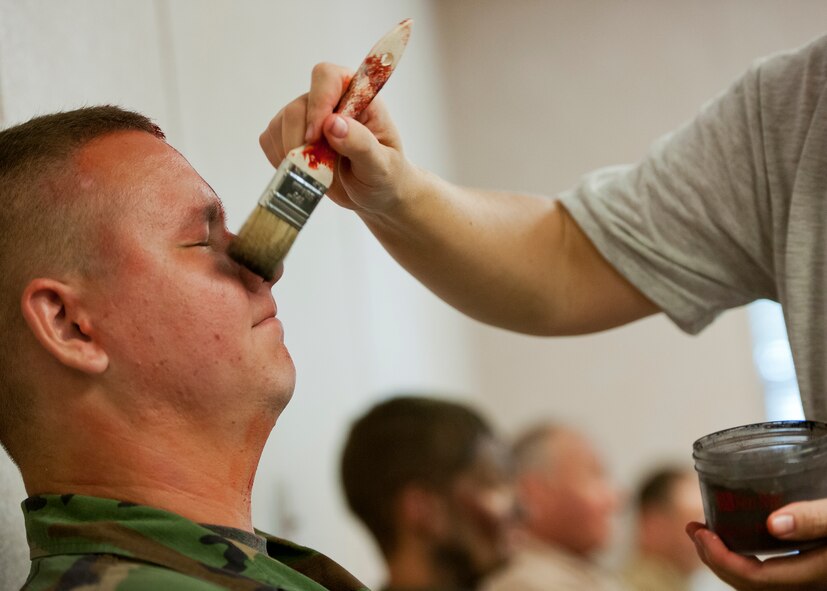 Senior Airman Christianson Parker, 919th Special Operations Support Squadron, gets a “dusting” of ash make up by a moulage team member prior to a recent exercise at Duke Field.  The 96th Medical Group's team of six Airmen provides a sense of realism in exercises that medics and first responders may encounter in real-world accidents. (U.S. Air Force photo/Tech. Sgt. Samuel King Jr.)