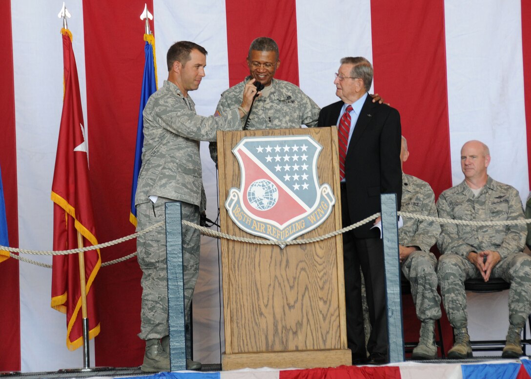 U.S. Air Force Maj. Ross Goodin, deputy commander of the 238th Air Support Operations Squadron, holds the microphone for Maj. Gen. Augustus Collins, the Adjutant General for Mississippi, as he delivers the aircraft launch command with special guest, U.S. Air Force retired, Brig. Gen. Sam Forbert during the base's 75th anniversary ceremony held on Key Field Air National Guard Base, Meridian, Miss., Sept. 6, 2014. The launching of the aircraft commemorated the founding of Key Field's original 153rd Observation Squadron in 1939.  (U.S. Air National Guard photo by Senior Airman Jessica Fielder/Released)