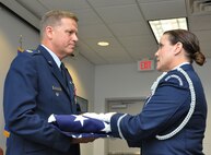 Col. Robert Mortensen, deputy director operations and plans at Tenth Air Force, accepts a flag from an honor guard member during his retirement ceremony Sep. 6, 2014, Naval Air Station Fort Worth Joint Reserve Base, Texas. He previously served as vice-commander of the 301st Fighter Wing from 2008 to 2010. (U.S. Air Force photo by Staff Sgt. Samantha Mathison)