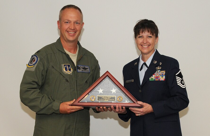 185th Air Refueling Wing Commander Col Larry Christensen presents Master Sgt. Amie Hanson with a U.S. flag on the occasion of her retirement on Sept 6, 2014 in Sioux City, Iowa. Hansen a long time unit member retired from the 185th Comptroller Flight after 28 years of service.