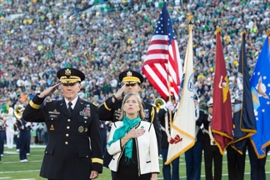 Army Gen. Martin E. Dempsey, chairman of the Joint Chiefs of Staff, and his wife, Deanie, render honors as the National Anthem is played before a football game between the University of Notre Dame and the University of Michigan at Notre Dame Stadium in South Bend, Ind., Sept. 6, 2014.