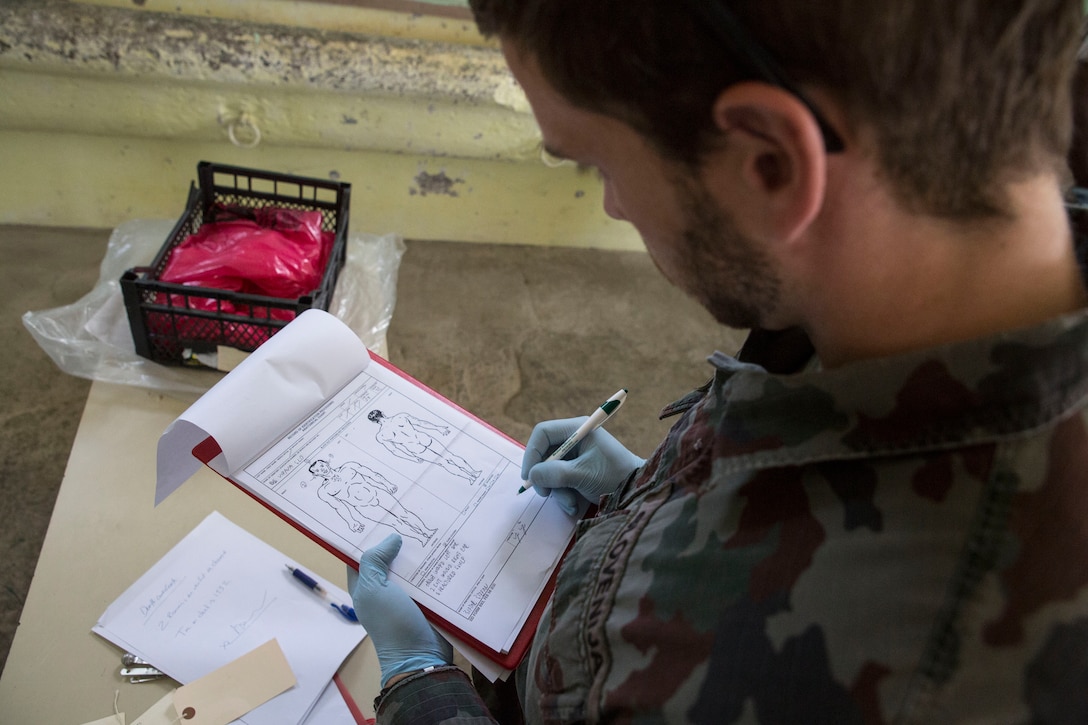 A Slovenian soldier takes necessary notes while documenting a simulated casualty with Marines from Personnel Retrieval and Processing Company, 4th Marine Logistics Group, Marine Forces Reserve, during the culminating event of exercise Immediate Response 2014 here, Aug. 25-27, 2014. (U.S. Marine Corps photo by Cpl. Codey Underwood)