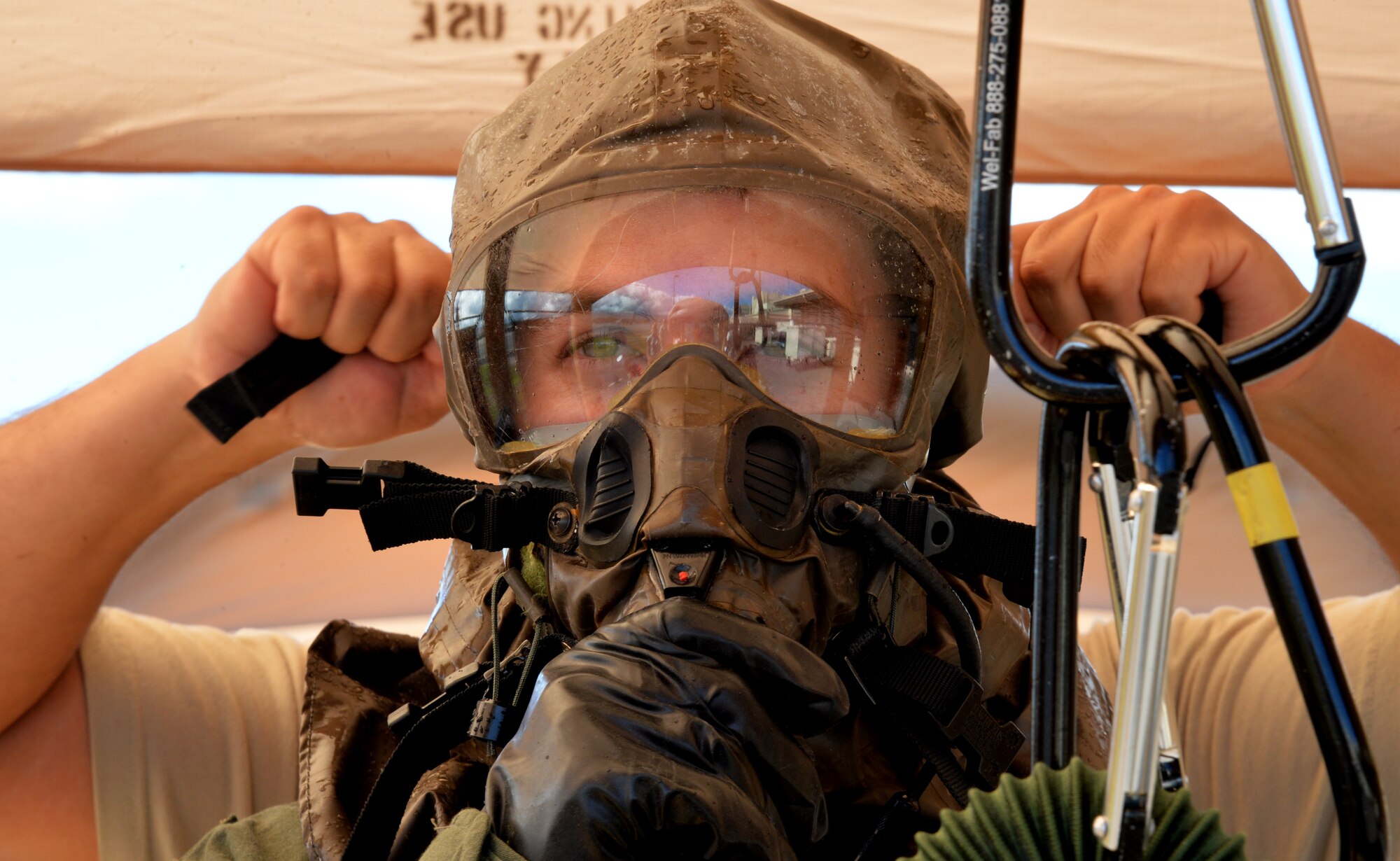Capt. Benjamin Deriggi, 96th Air Refueling Squadron, has his gasmask straps tightened by Master Sgt. Carlos Diaz, Hawaii Air National Guard 199th Fighter Squadron, during an emergency preparedness training event Sept. 5, 2014, at Joint Base Pearl Harbor-Hickam, Hawaii. Deriggi and other 96th ARS members participated in the chemical, biological, radiological and nuclear training that ensures they are prepared to operate in a contaminated environment. Diaz and his team from the 15th OSS and 199th Fighter Squadron aircrew flight equipment sections manned decontamination stations as part of the Aircrew Contamination Control Area, which aircrew members had to pass through to conclude the training. Note: In a real-world CBRN environment, the AFE crew would also be in individual protective equipment. (U.S. Air Force photo by Staff Sgt. Alexander Martinez)