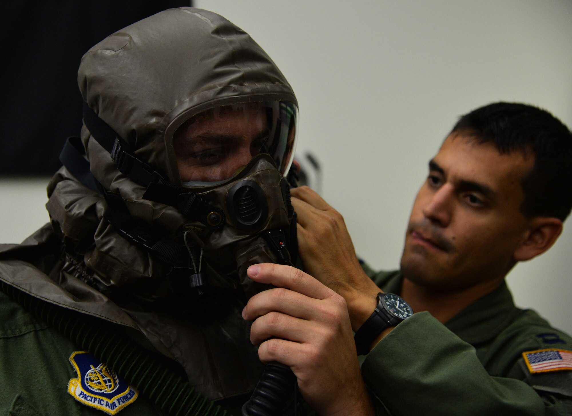 Capt. Daniel Montilla, 96th Air Refueling Squadron, assists Capt. Victor Stafford, 96th ARS, with putting on an Aircrew Eye and Respiratory Protection System during an emergency preparedness training event Sept. 5, 2014, at Joint Base Pearl Harbor-Hickam, Hawaii. Montilla, Stafford and other 96th ARS members participated in the chemical, biological, radiological and nuclear training that ensures they are prepared to operate in a contaminated environment. (U.S. Air Force photo by Staff Sgt. Alexander Martinez)