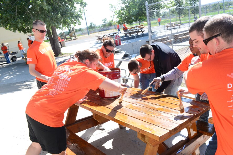 Airmen and community volunteers team up to stain picnic tables at the Star of the West Sports Complex in Rapid City, S.D., during the United Way Day of Caring, Sept. 4, 2014. During the event, Airmen and other volunteers actively gave back to their community by completing various projects, including washing windows, cleaning out gutters, mowing lawns, putting up chain-link fences, painting homes and similar activities. (U.S. Air Force photo by Senior Airman Zachary Hada/Released)