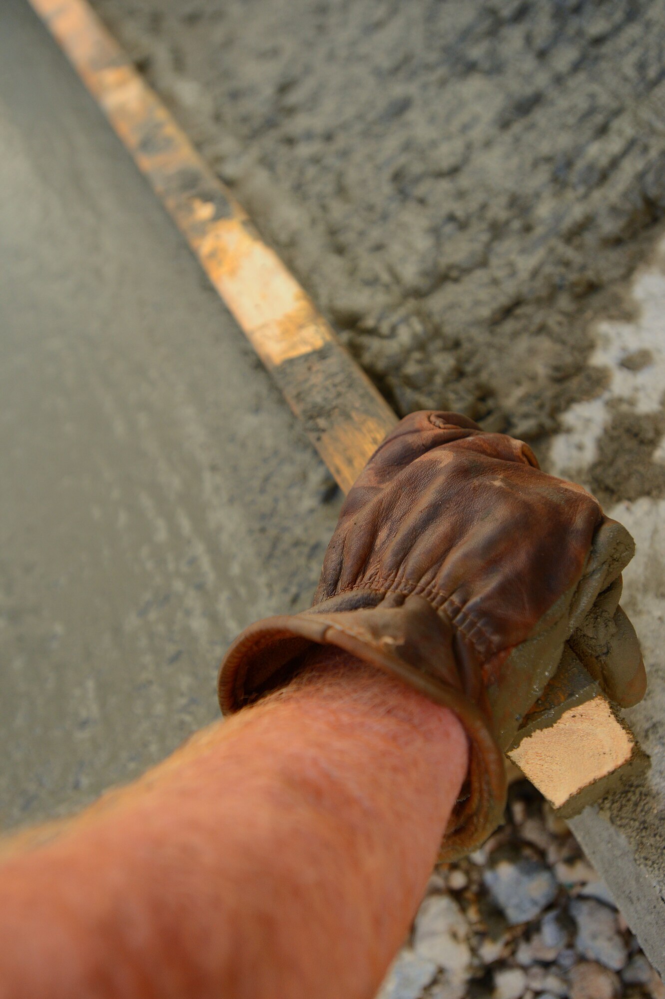 A 20th Civil Engineer Squadron horizontal repair Airman smoothes the surface of wet concrete at Shaw Air Force Base, S.C., Sept. 4, 2014. During a process called “screeding”, a flat, long piece of material is used to smooth the top layer of concrete immediately after being laid on a surface. (U.S. Air Force photo by Airman 1st Class Jensen Stidham/Released)