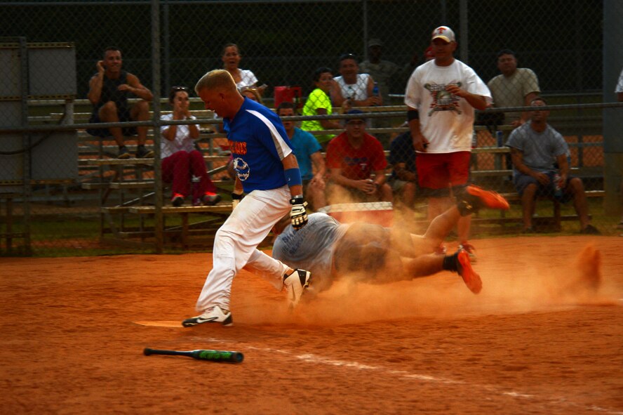 U.S. Air Force Senior Master Sgt. Charles Godfrey, 20th Aircraft Maintenance Squadron superintendent, steps on home plate during the intramural softball championship at Shaw Air Force Base, S.C., Sept. 2, 2014. While Godfrey ran towards home plate, a 20th Civil Engineer Squadron firefighter caught the softball and attempted to tag him out. (U.S. Air Force photo by Airman 1st Class Jensen Stidham/Released)