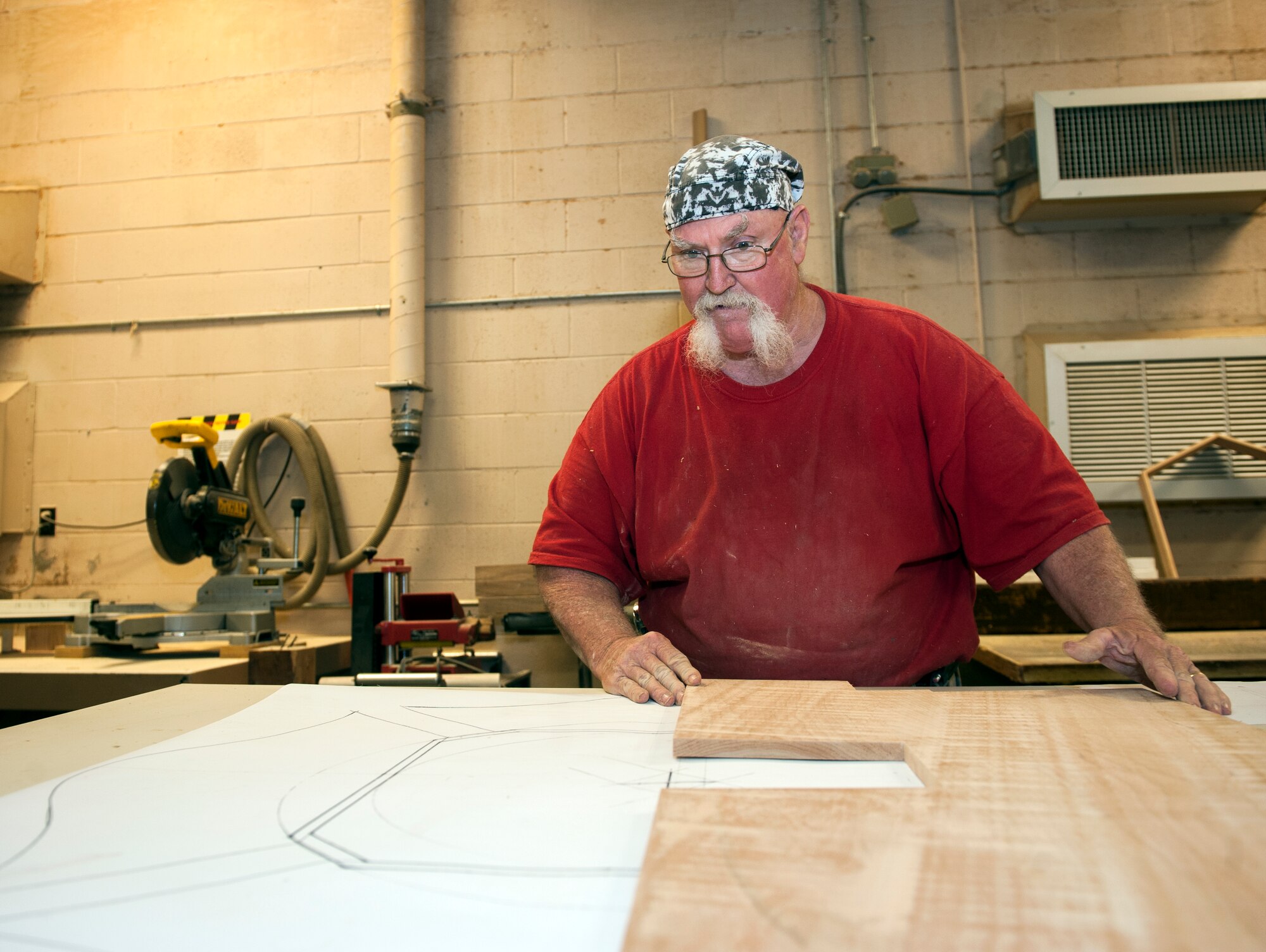John Fischbach Sr., 23d Force Support Squadron recreation aide, references blueprints while working on a shadow box Aug. 1, 2014, at Moody Air Force Base, Ga. As the sole woodworker in the Moody woodshop, Fischbach plans, designs and constructs everything from shadow boxes and plaques to bullet-shot glasses. (U.S. Air Force photo by Senior Airman Jarrod Grammel/Released)
