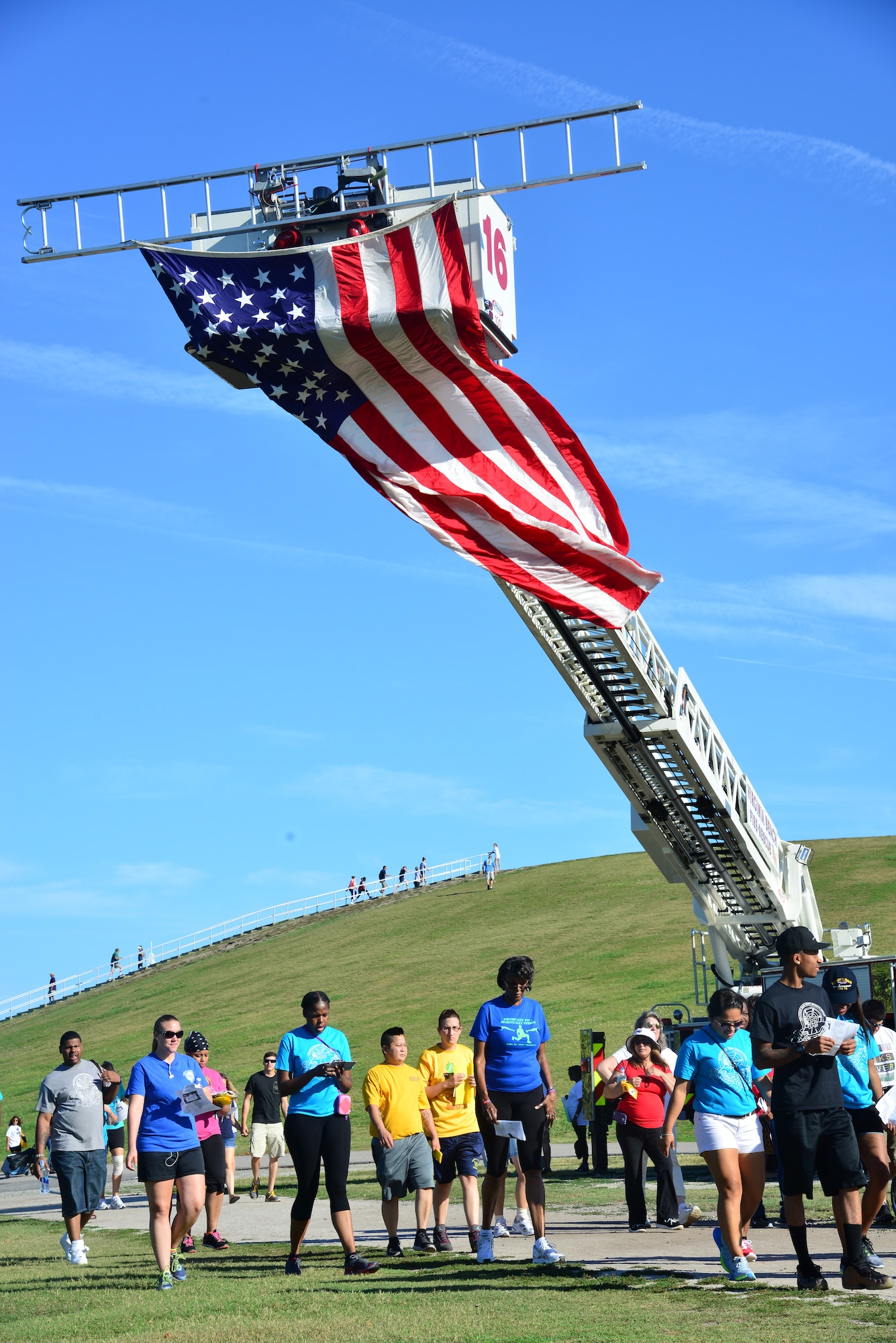 Out of the Darkness community walk supporters stroll underneath an American flag during the walk in Virginia Beach, Va., Sept. 6, 2014. According to the American Foundation for Suicide Prevention, suicide is the fourth leading cause of death in the U.S. among adults ages 18 – 65, and the second leading among teens and young adults. (U.S. Air Force photo by Senior Airman Aubrey White/Released)