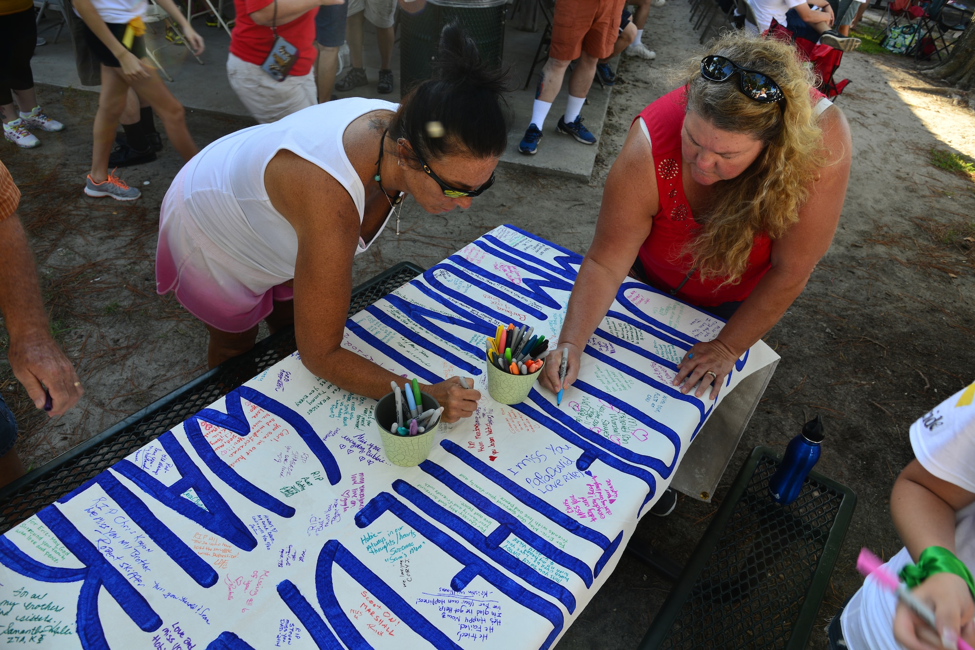 Hampton Roads community members write personal messages on a banner before the start of the Out of Darkness community walk in Virginia Beach, Va., Sept. 6, 2014. Walk supporters had the opportunity to seek onsite counseling and mental health resources during the mental health awareness event. (U.S. Air Force photo by Senior Airman Aubrey White/Released)