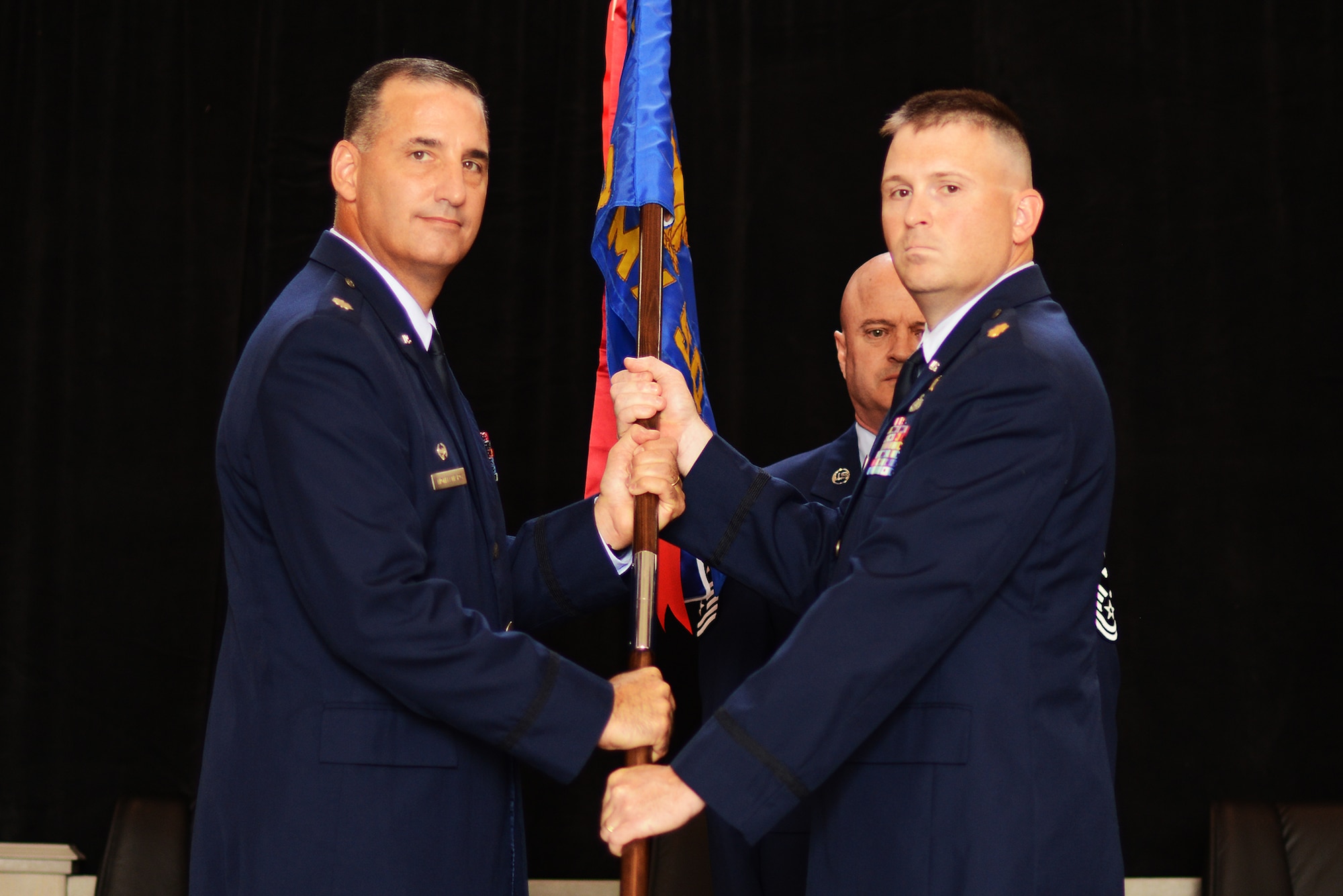 Lt. Col. Christopher Montanaro, 189th Maintenance Group commander, passes the guidon to Maj. Christopher Wolter, 189th Aircraft Maintenance Squadron commander, during a change of command at Hangar 207, Little Rock Air Force Base, Sept. 6, 2014. Wolter comes from the 189th Communications Flight where he served as the commander for more than three years.