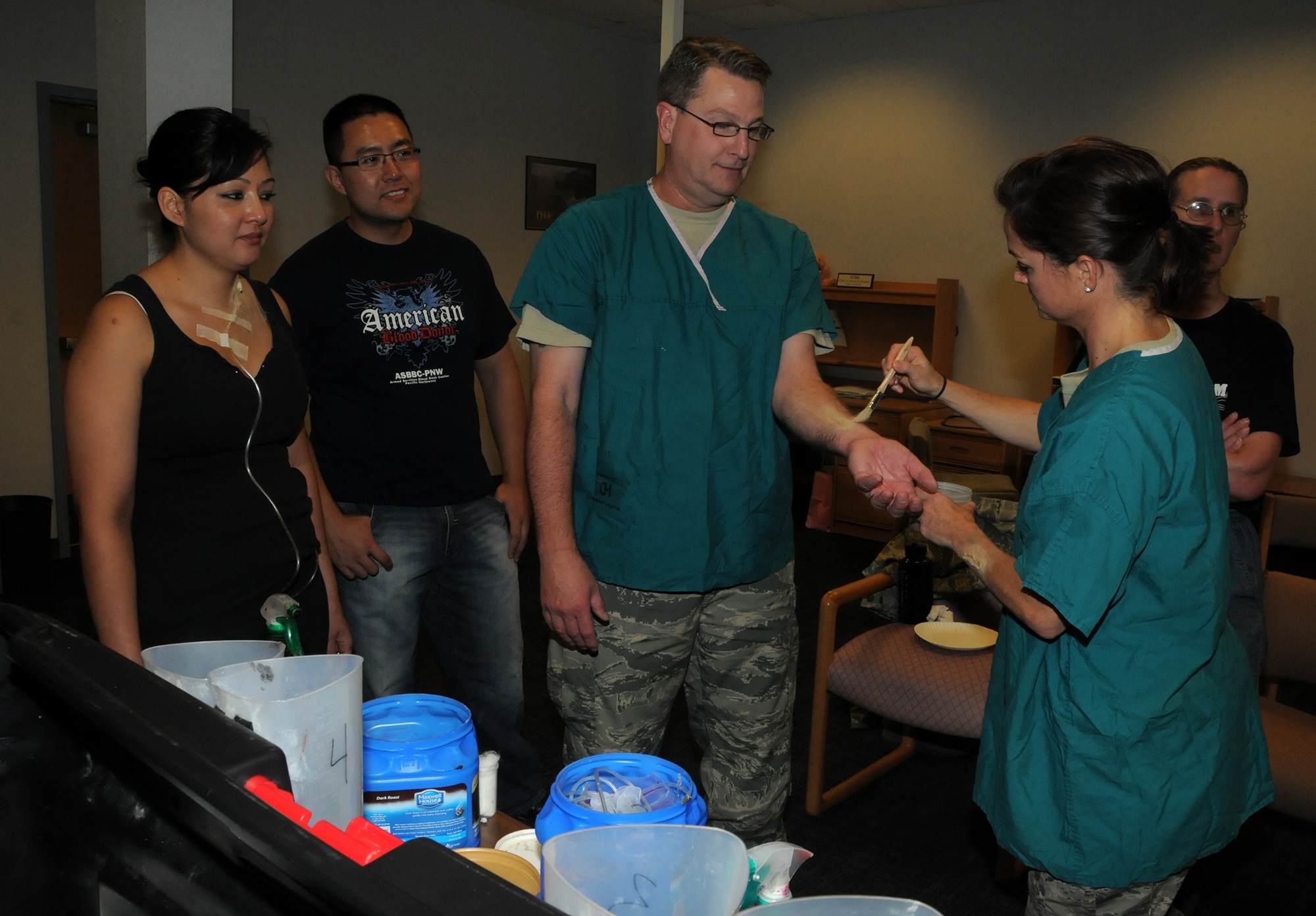 WRIGHT PATTERSON AIR FORCE BASE, Ohio – Tech. Sgt. Holly Siripavaket applies moulage to Master Sgt. Todd Noe’s arm to simulate an arm wound as Master Sgt. Julie Turner and Staff Sgt. Yvan Fang look on. All are assigned to the 445th Aerospace Medicine Squadron. Moulage is used to create realistic wounds during a mass casualty training exercise, enhancing the realism of a scenario involving victims. (U.S. Air Force photo/Tech. Sgt. Anthony Springer)