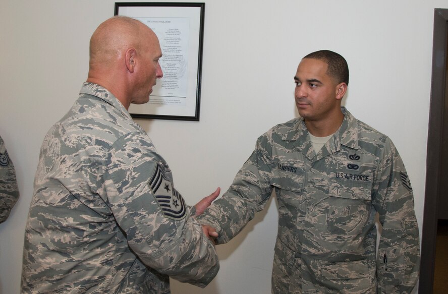 U.S. Air Force Staff Sgt. Randal Landers, 23d Civil Engineer Squadron infrastructures, receives a coin from Chief Master Sgt. Scott Fuller, 9th Air Force command chief, Sept. 4, 2014, at Moody Air Force Base, Ga. During his visit, the Chief coined several Airmen who were nominated by their senior leadership for hard work and performance. (U.S. Air Force photo by Staff Sgt. Eric Summers Jr. /Released)