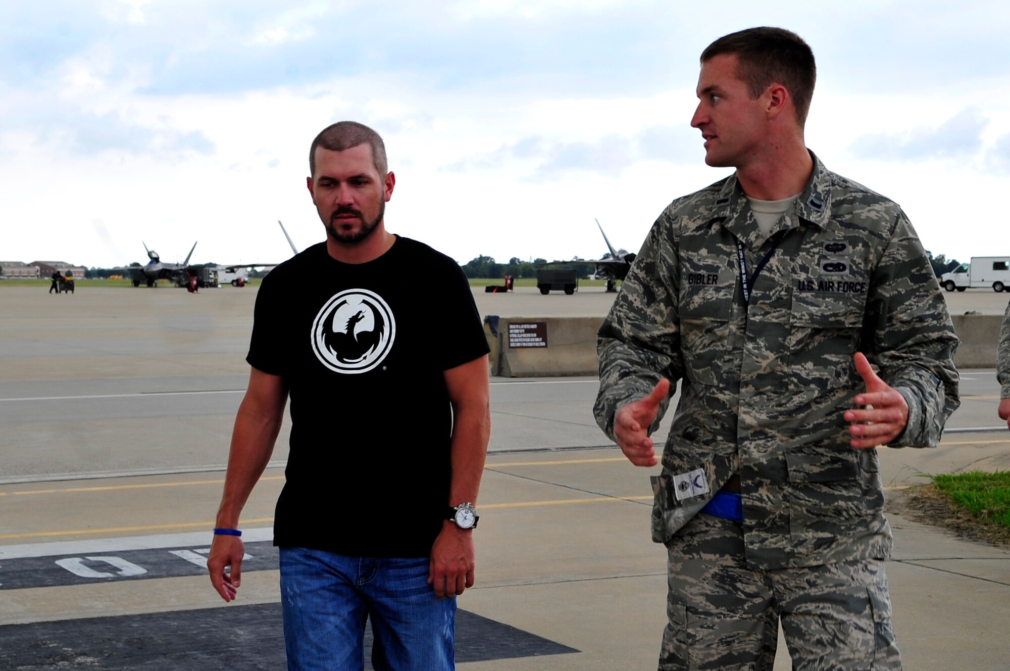 U.S Air Force 1st Lt. Andrew Gibler, 1st Maintenance Squadron assistant officer-in-charge, talks to Michael Annett, NASCAR driver, about the F-22 Raptor during a tour of Langley Air Force Base, Va., Sept. 4, 2014. Annett came to Langley to learn more about the base and its mission. (U.S. Air Force photo by Airman 1st Class Breonna Veal/Released) (Photo was cropped and color corrected to emphasize subject.)