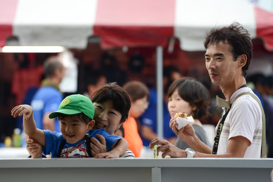 A family greets friends during the 2014 Japanese-American Friendship Festival at Yokota Air Base, Japan, Sept. 6, 2014. More than 148,000 people attended to two-day festival to enjoy a variety of cuisines, see aircraft and learn about the U.S.-Japan alliance. (U.S. Air Force photo by Staff Sgt. Cody H. Ramirez/Released)