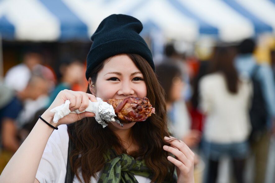 A woman finds it hard to hide a smile while enjoying a turkey leg at the 2014 Japanese-American Friendship Festival at Yokota Air Base, Japan, Sept. 7, 2014. During the two-day festival, Yokota hosted more than 148,000 attendees. The festival featured a variety of U.S. and Japanese military aircraft and offered an array of food booths and multicultural entertainment. (U.S. Air Force photo by Staff Sgt. Cody H. Ramirez/Released)