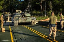 Lance Cpl. Keondre Mitchell, an M1A1 Abrams tank mechanic with 2nd Tank Battalion, 2nd Marine Division, drives a tank onto an M17 floating raft, guided by Cpl. Alexander Tafoya, a combat engineer for Bridge Company, 8th Engineer Support Battalion, 2nd Marine Logistics Group, during a training exercise aboard Marine Corps Base Camp Lejeune, N.C., Sept. 4, 2014. The raft can carry two 70-ton tanks across small bodies of water, while being towed and guided by two Mach 3 Bridge Erection Boats. (U.S. Marine Corps photo taken by Lance Cpl. Alex W. Mitchell/released)