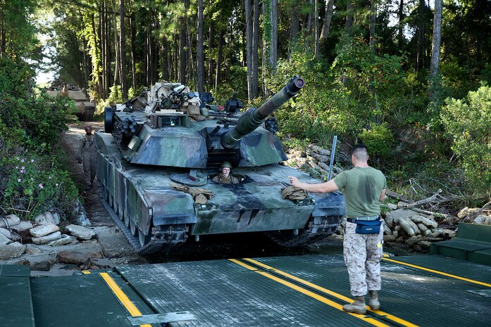 Private 1st Class Nicholas Singler, an M1A1 Abrams tank mechanic for 2nd Tank Battalion, 2nd Marine Division, drives a tank onto an M17 floating raft, while being guided by Cpl. Alexander Tafoya, a combat engineer for Bridge Company, 8th Engineer Support Battalion, 2nd Marine Logistics Group, during a training exercise aboard Marine Corps Base Camp Lejeune, N.C., Sept. 4, 2014. The raft can carry two 70-ton tanks across small bodies of water, while being towed and guided by two Mach 3 Bridge Erection Boats. (U.S. Marine Corps photo taken by Lance Cpl. Alex W. Mitchell/released)