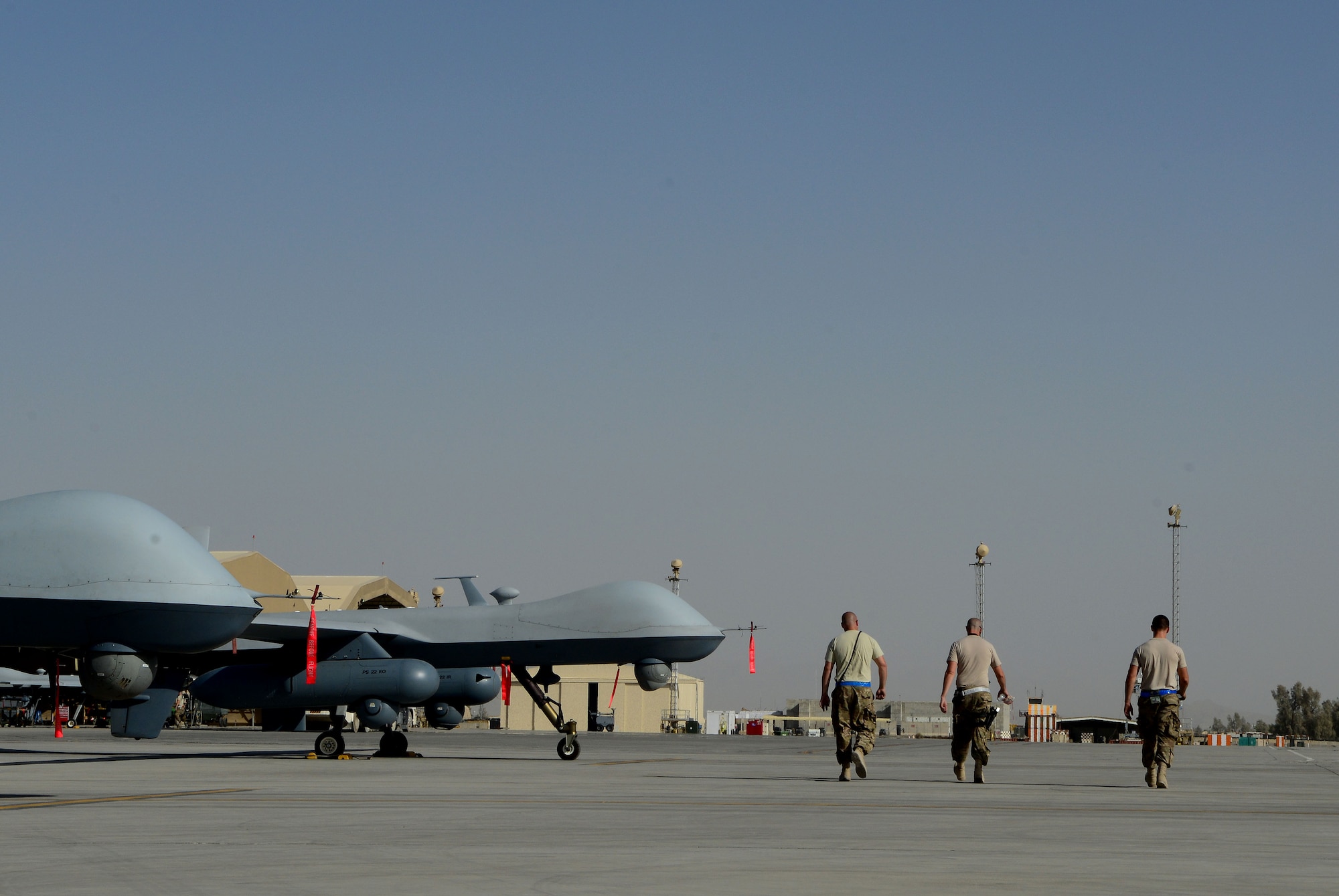 Aircraft armament systems specialists walk past MQ-9 Reapers with the 62nd Expeditionary Reconnaissance Squadron Aug. 18, 2014, at Kandahar Airfield, Afghanistan. The Reaper is launched, recovered and maintained here. It is also remotely operated by pilots in bases located in the U.S. The Airmen are with the 451st Expeditionary Aircraft Maintenance Squadron. (U.S. Air Force photo/Staff Sgt. Evelyn Chavez)