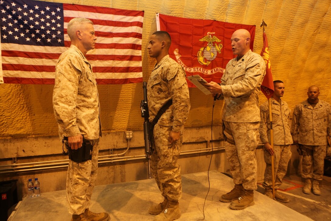 Sergeant Maj. Micheal Barrett, right, the 17th Sergeant Major of the Marine Corps, reads the meritorious promotion warrant of Lance Cpl. Miguel Mercedes, an ammunition technician specialist with Redeployment and Retrograde in support of Reset and Reconstitution Operations Group, during his meritorious promotion ceremony aboard Camp Leatherneck, Afghanistan, Sept. 6, 2014. General James F. Amos, the 35th Commandant of the Marine Corps, meritoriously promoted Mercedes, a native of Bronx, New York, to the rank of corporal during his final visit to Helmand province.