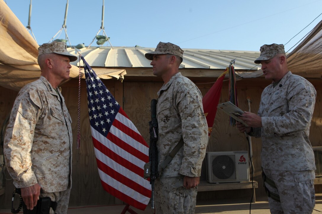 Sergeant Maj. Micheal Barrett, right, the 17th Sergeant Major of the Marine Corps, reads the meritorious promotion warrant of Corporal Dominic Sharpsteensurina, an assault section leader with Charley Company, 1st Battalion, 7th Marine Regiment, during his meritorious promotion ceremony aboard Camp Leatherneck, Afghanistan, Sept. 6, 2014. General James F. Amos, the 35th Commandant of the Marine Corps, meritoriously promoted Sharpsteensurina, a native of Minneapolis, to the rank of sergeant during his final visit to Helmand province.