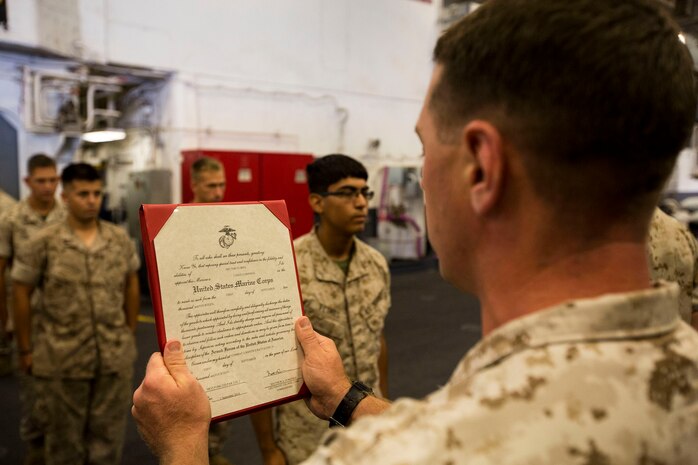 Gunnery Sgt. Jonathan J. Croake, the engineer chief for Combat Engineer Platoon, Combat Logistics Battalion 24, 24th Marine Expeditionary Unit, reads a promotion warrant for Pfc. Hector Flores, a combat engineer with CLB-24, and a Glendale Heights, Ill., native, as he is being promoted to lance corporal during a promotion ceremony during an operational pause of Amphibious Ready Group/Marine Expeditionary Unit Exercise aboard the USS Iwo Jima, at sea, Sept. 9, 2014. ARG/MEU-Ex is the first at sea evaluations Expeditionary Operations Training Group is conducting and is the third major predeployment exercise in preparation of the deployment at the end of the year. (U.S. Marine Corps photo by Sgt. Devin Nichols/Released)