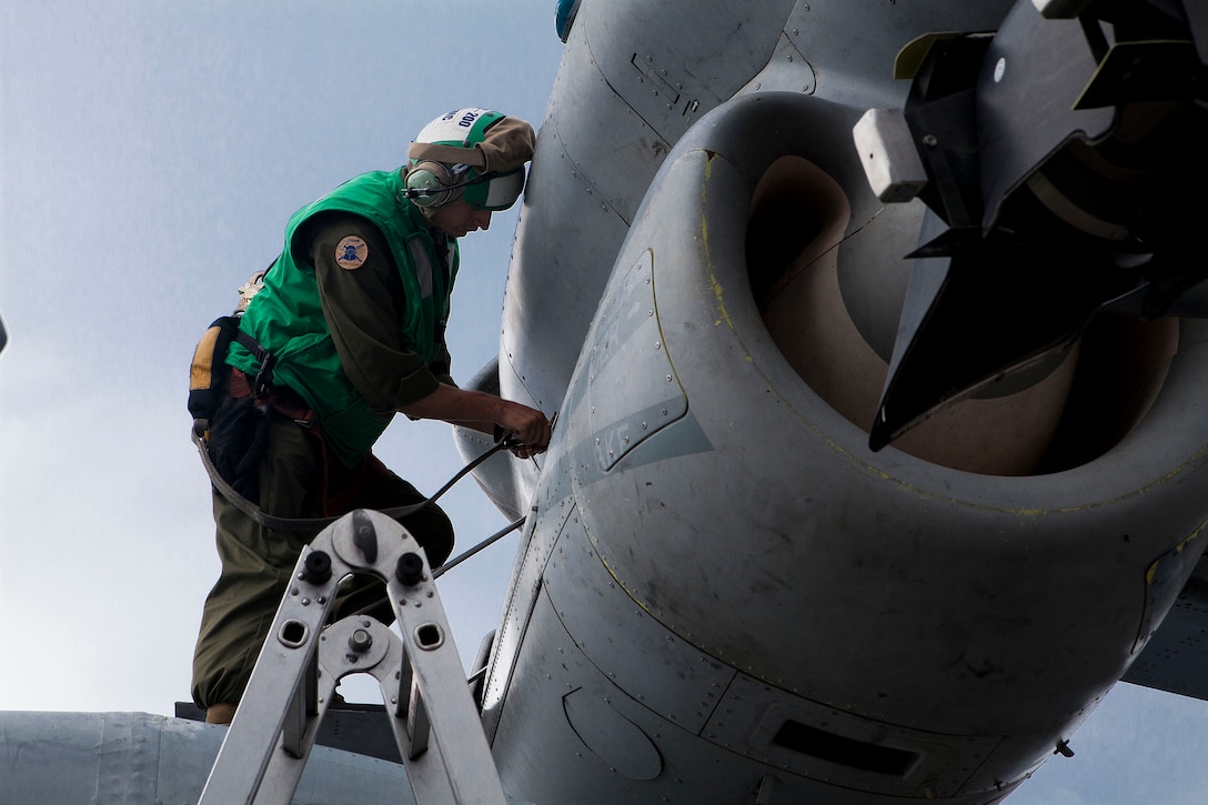 Staff Sgt. Brent E. Sarver Jr., an avionics technician with Marine Medium Tiltrotor Squadron 365 (Reinforced), 24th Marine Expeditionary Unit, and a Canton, Ohio, native, places tape on a MV-22B Osprey to allow the exhaust fumes to deflect ...off the tilt-rotor during Amphibious Ready Group/Marine Expeditionary Unit Exercise aboard the USS Iwo Jima off the coast of North Carolina, Sept. 7, 2014. Each aircraft aboard the ship must undergo several hours of preventive maintenance and quality assurance checks to maintain their flight-ready status.