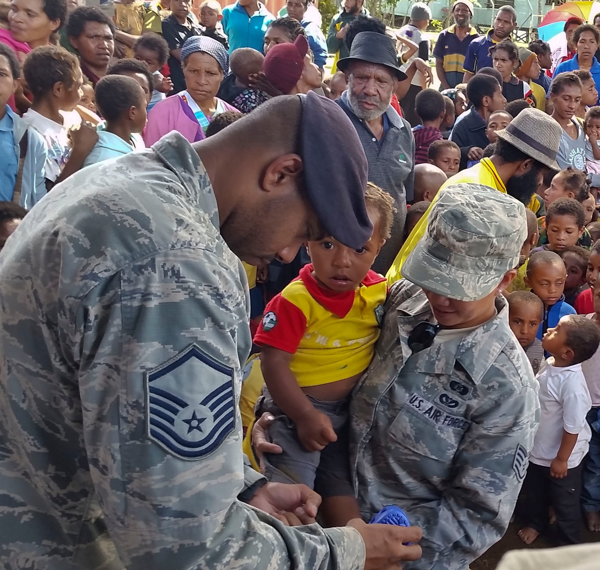 Master Sgt. Jamain Braxton, the anti-terrorism officer for Pacific Unity 14-8 deployed from Andersen Air Force Base, Guam, tries a pair of shoes on a child during a shoe drive for the local community of Mount Hagen, Papua New Guinea, Sept. 8, 2014. While deployed in support of Pacific Unity Braxton organized the shoe drive to benefit children in the community. Pacific Unity helps cultivate common bonds and foster goodwill between the U.S. and regional nations through multilateral humanitarian assistance and civil military operations. (U.S. Air Force photo by Airman 1st Class Jaimie Aquino/Released)