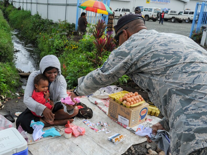 Master Sgt. Jamain Braxton, the anti-terrorism officer for Pacific Unity 14-8 deployed from Andersen Air Force Base, Guam, hands a pair of shoes to a mother and her child in the local community of Mount Hagen, Papua New Guinea, Sept. 8, 2014. While deployed in support of Pacific Unity, Braxton organized a shoe drive to benefit children in the local community. Pacific Unity helps cultivate common bonds and foster goodwill between the U.S. and regional nations through multilateral humanitarian assistance and civil military operations. (U.S. Air Force photo by Tech. Sgt. Terri Paden/Released)