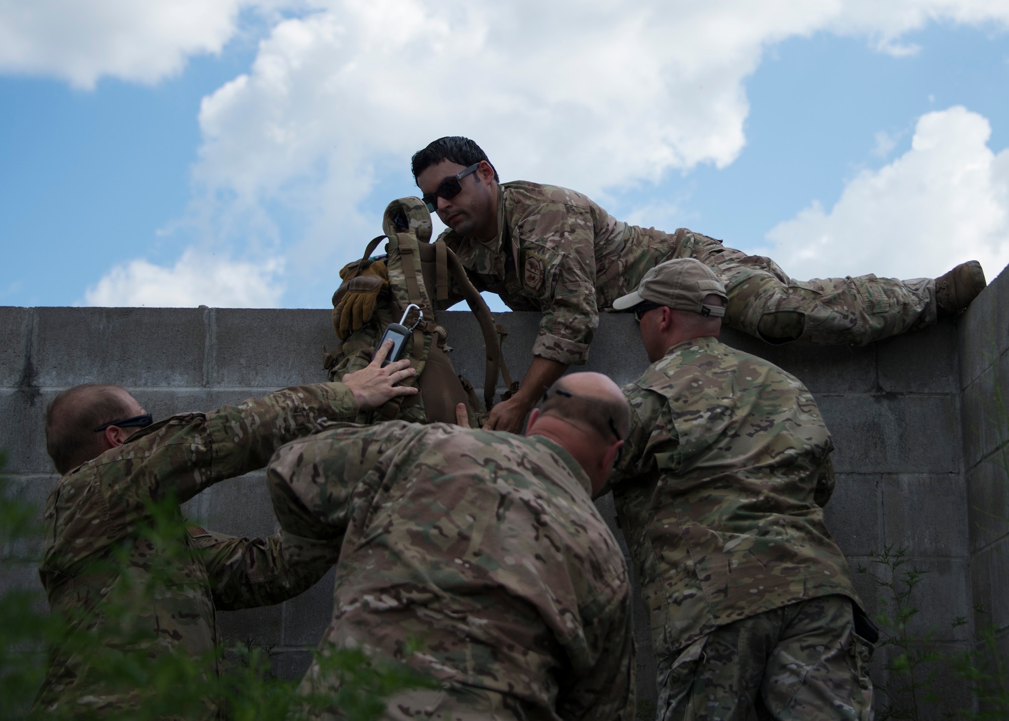 Staff Sgt. Juan Acevedo, 919th Special Operations Security Forces Squadron, grabs his gear before proceeding over the wall during a culmination exercise on the Eglin Air Force Base range, Aug. 27.  Duke Field’s reserve combat aviation advisors joined their active-duty counterparts for a five-day exercise of specialized spin-up training.  The Airmen move on to the Joint Readiness Training Center at Fort Polk, La., for further development. (U.S. Air Force photo/Tech. Sgt. Jasmin Taylor)