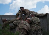 Staff Sgt. Juan Acevedo, 919th Special Operations Security Forces Squadron, grabs his gear before proceeding over the wall during a culmination exercise on the Eglin Air Force Base range, Aug. 27.  Duke Field’s reserve combat aviation advisors joined their active-duty counterparts for a five-day exercise of specialized spin-up training.  The Airmen move on to the Joint Readiness Training Center at Fort Polk, La., for further development. (U.S. Air Force photo/Tech. Sgt. Jasmin Taylor)