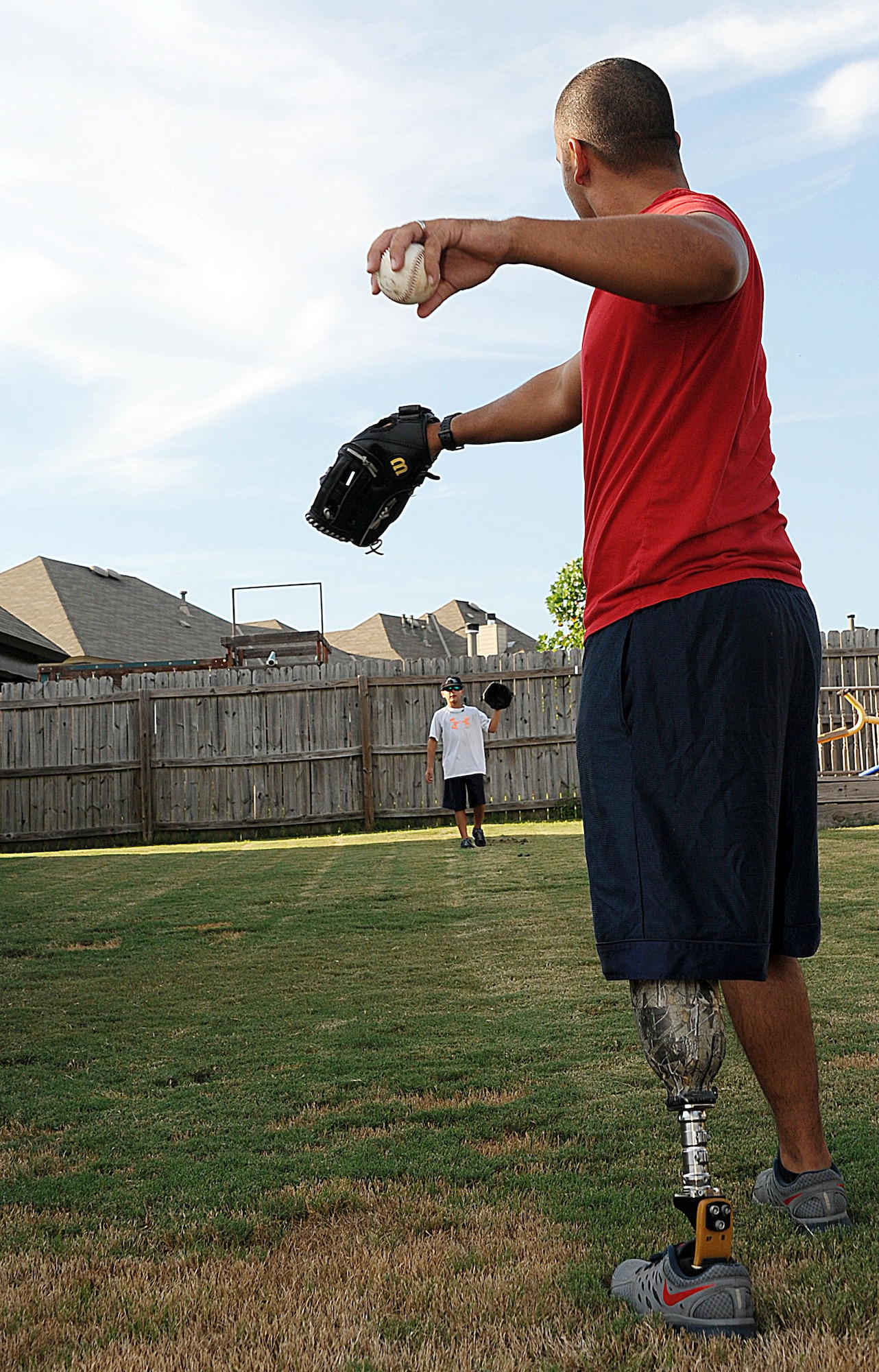 Staff Sgt. Rey Edenfield, a Maxwell Air Force Base air traffic controller, plays catch with his son, Dawson, in the backyard of their family home Aug. 28. Edenfield was involved in a motorcycle accident that resulted in the family decision to amputate his left leg six inches below the knee. Edenfield’s prosthetic allows him to not only stay on active duty, but also to be a more active husband and father. (U.S. Air Force photo by Staff Sgt. Erica Picariello)