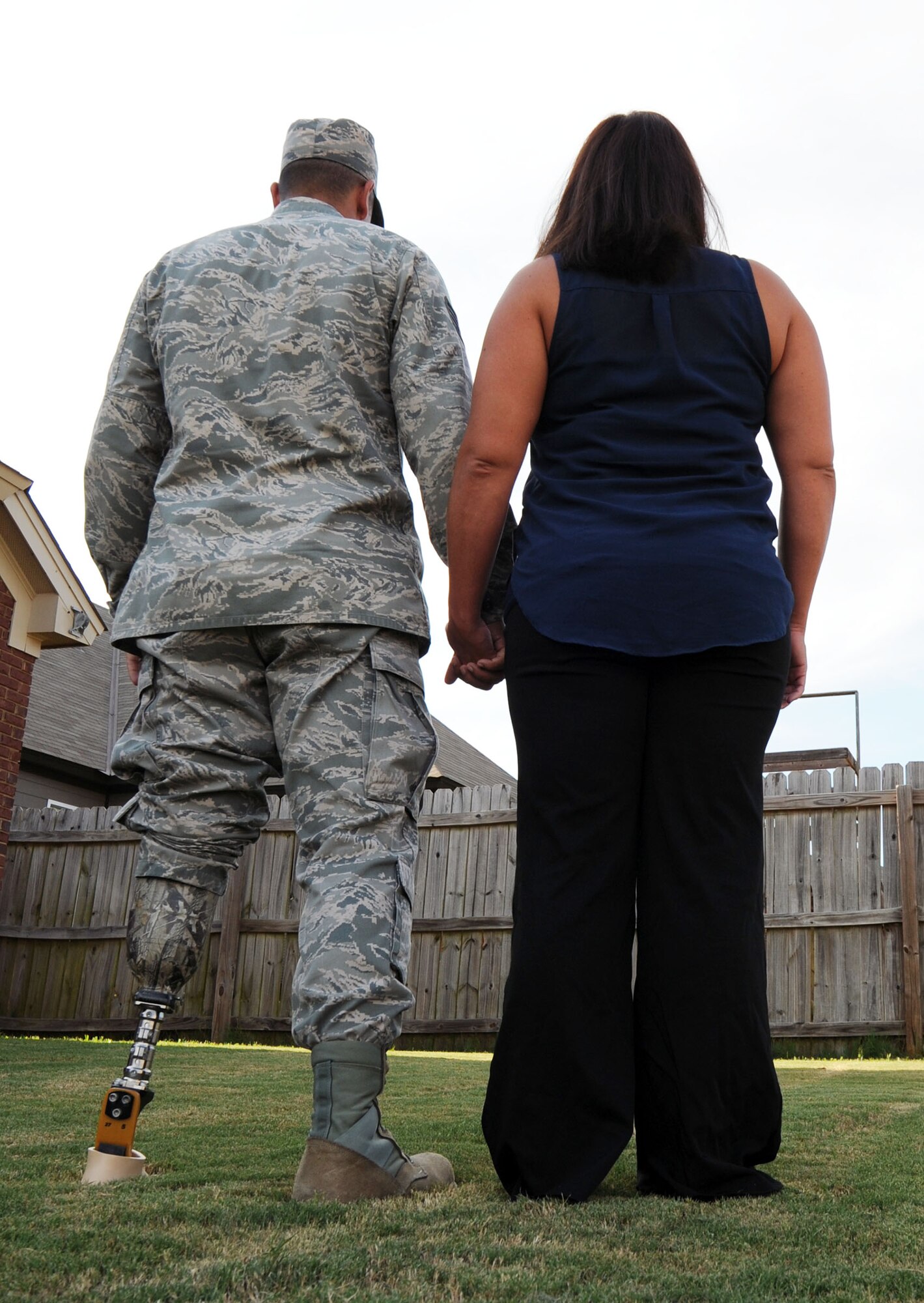 Staff Sgt. Rey Edenfield holds the hand of his wife, Amy, in their backyard Aug.28. Edenfield, a Maxwell Air Force Base air traffic controller, had his leg amputated almost a year ago after a motorcycle accident. (U.S. Air Force photo by Staff Sgt. Erica Picariello)