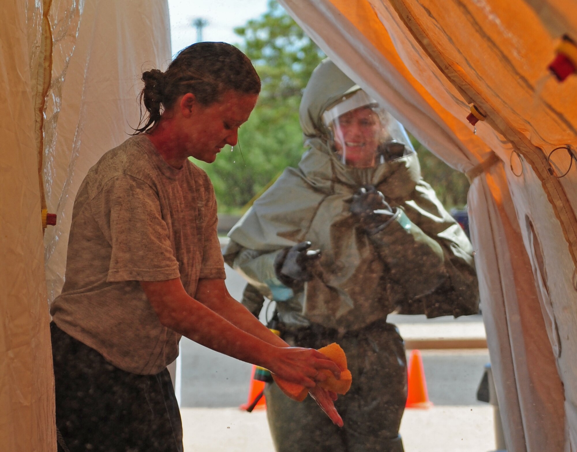 A simulated victim of a jet fuel explosion scrubs “contaminants” off of her skin during in-place patient decontamination (IPPD) training Sept. 4, 2014, at Dyess Air Force Base, Texas. IPPD training is designed to prepare Airmen to provide care in the event of a chemical, biological, radiological or nuclear catastrophe. (U.S. Air Force photo by Senior Airman Kia Atkins/Released)