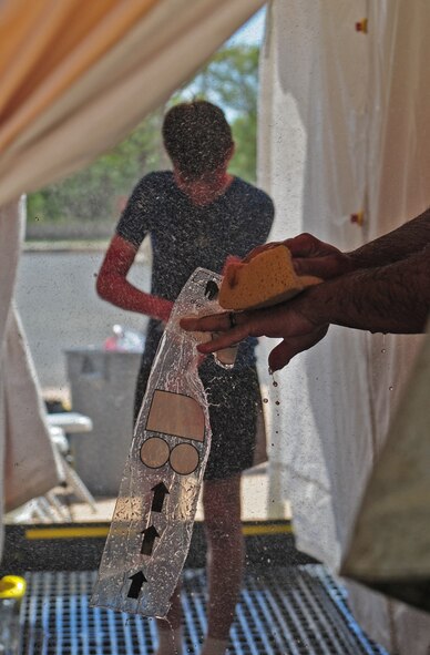Simulated victims of a jet fuel explosion scrub “contaminants” off of their bodies during in-place patient decontamination (IPPD) training Sept. 4, 2014, at Dyess Air Force Base, Texas. After the potential contaminant was determined, each patient was assessed and triaged, where the IPPD team performed life-saving measures and efficiently decontaminated each patient. (U.S. Air Force photo by Senior Airman Kia Atkins/Released)