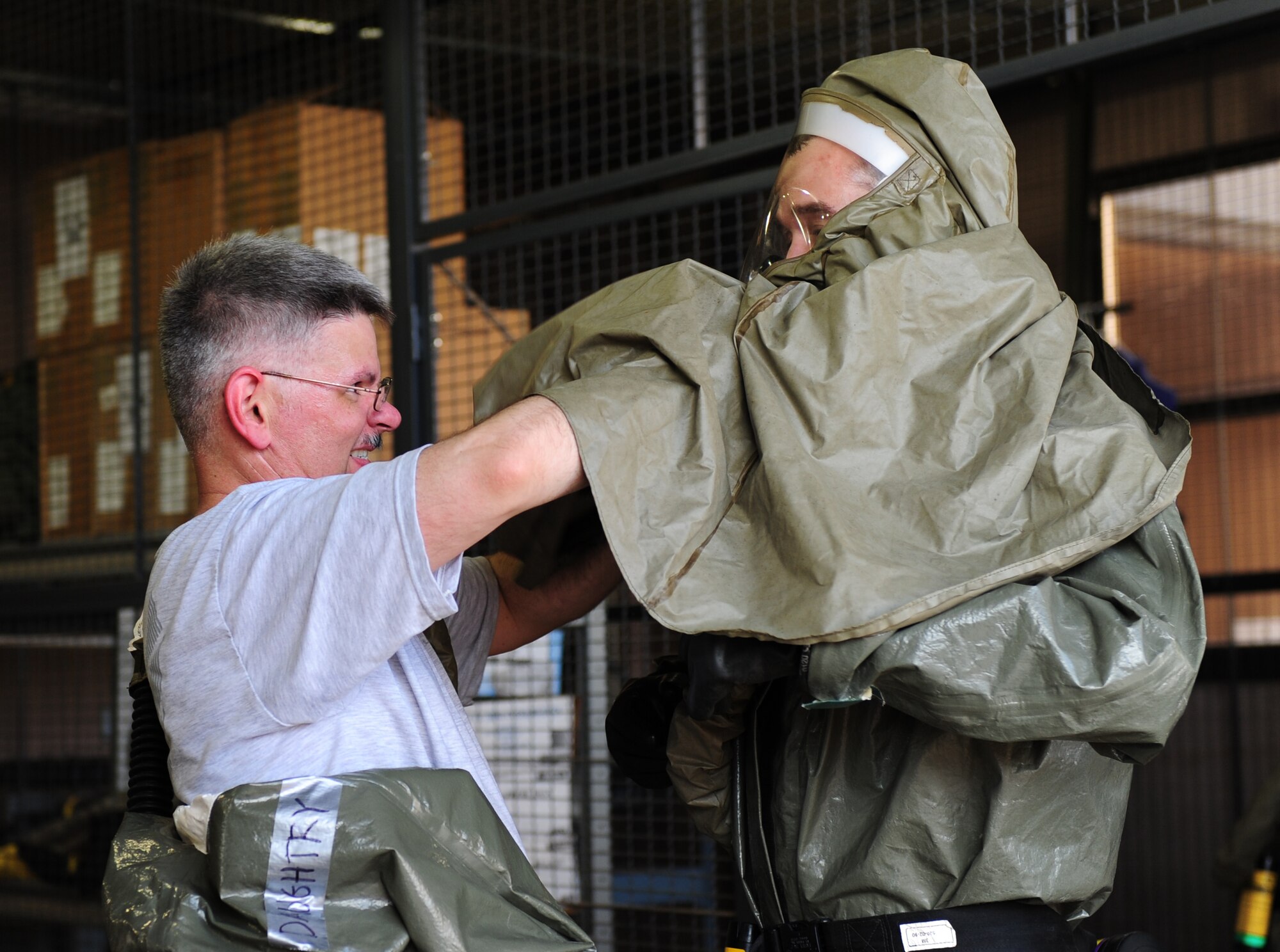 U.S. Air Force Master Sgt. Matthew Daughtry, left, helps Maj. Scott Walker, both from the 7th Aerospace Medicine Squadron, don his powered air purifying respirator suit during in-place patient decontamination training (IPPD) Sept. 4, 2014, at Dyess Air Force Base, Texas. The IPPD training taught Airmen how to care for patients in hazardous situations and construct a decontamination facility. (U.S. Air Force photo by Senior Airman Kia Atkins/Released)