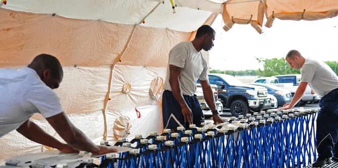U.S. Air Force Airmen from the 7th Medical Group put together an articulating frame shelter during training for their in-place patient decontamination (IPPD) team Sept. 4, 2014, at Dyess Air Force Base, Texas. IPPD is designed to help patients who are injured to the point that they are unable to perform unaided decontamination. (U.S. Air Force photo by Senior Airman Kia Atkins/Released)