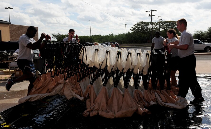 U.S. Air Force Airmen from the 7th Medical Group raise an articulating frame shelter as part of in-place patient decontamination (IPPD) training Sept. 4, 2014, at Dyess Air Force Base, Texas. The goal of this training is to ensure the IPPD team is able to receive and triage patients within 15 minutes and be fully functional within 20 minutes of a chemical, biological, radiological or nuclear emergency notification. (U.S. Air Force photo by Senior Airman Kia Atkins/Released)