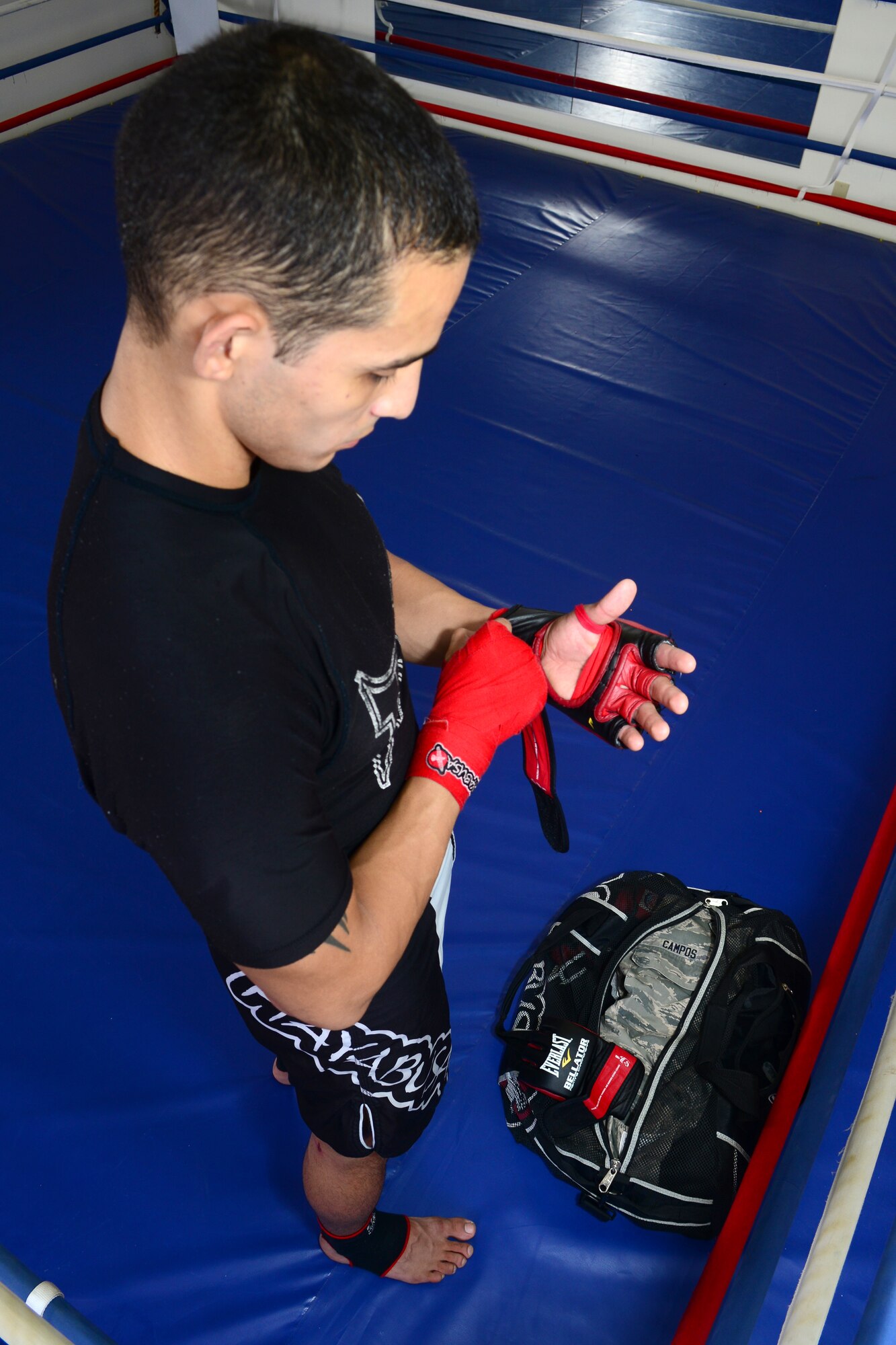 U.S. Air Force Airman 1st Class Juston Campos, 36th Intelligence Squadron target development analyst, slips on his sparring gloves at a martial arts academy in Newport News, Va., Sep. 8, 2014. Campos has spent the past few years balancing his life between mixed martial arts, college, his career and his family. His record is four wins, zero draws and zero losses. (U.S. Air Force photo by Airman 1st Class Devin Scott Michaels)(This photo's levels were adjusted for aesthetic purposes.)