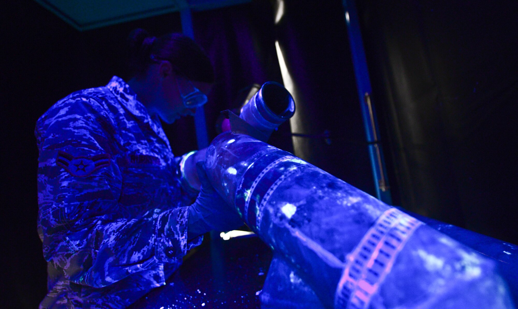 Airman 1st Class Amber Burns, 28th Maintenance Squadron non-destructive inspection apprentice, examines a fuel manifold tube soaked in penetrant liquid for cracks under ultra-violet light during an inspection at Ellsworth Air Force Base, S.D., Sept. 8, 2014. It is vital to let the penetrant liquid completely absorb into a part allowing imperfections to be identified under ultra-violet light. (U.S. Air Force photo by Senior Airman Zachary Hada/Released)