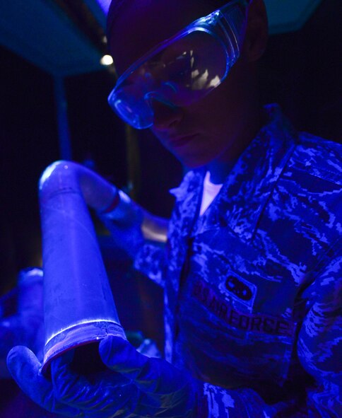 Airman 1st Class Amber Burns, 28th Maintenance Squadron non-destructive inspection apprentice, examines a fuel manifold tube for cracks under ultra-violet light during an inspection at Ellsworth Air Force Base, S.D., Sept. 8, 2014. The NDI flight inspects support equipment and aircraft and weapon system components for structural damage, flaws, cracks, voids, heat damage and stress fractures. (U.S. Air Force photo by Senior Airman Zachary Hada/Released)