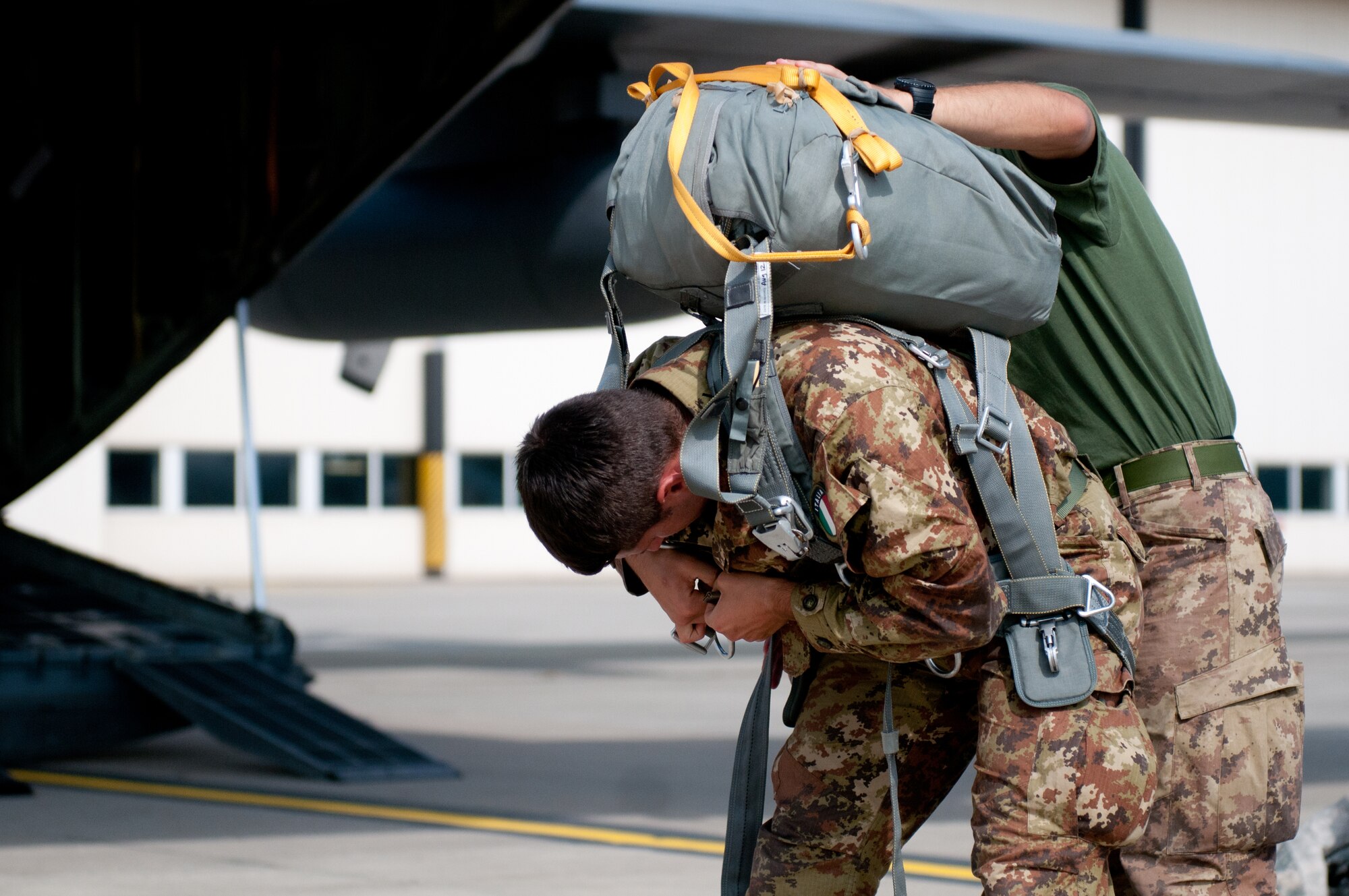 Italian Army Cpl. Felerico Yagliaroll of the 186th Parachute Regiment receives assistance with his gear from a fellow Italian Soldier as he prepares to board a Kentucky Air National Guard C-130 Hercules aircraft at Ramstein Air Base, Germany, Sept. 5, 2014, during Operation Saber Junction. Yagliaroll's unit is participating in the operation with troops from 17 NATO countries. (U.S. Air National Guard photo by 2nd Lt. James W. Killen/Released)