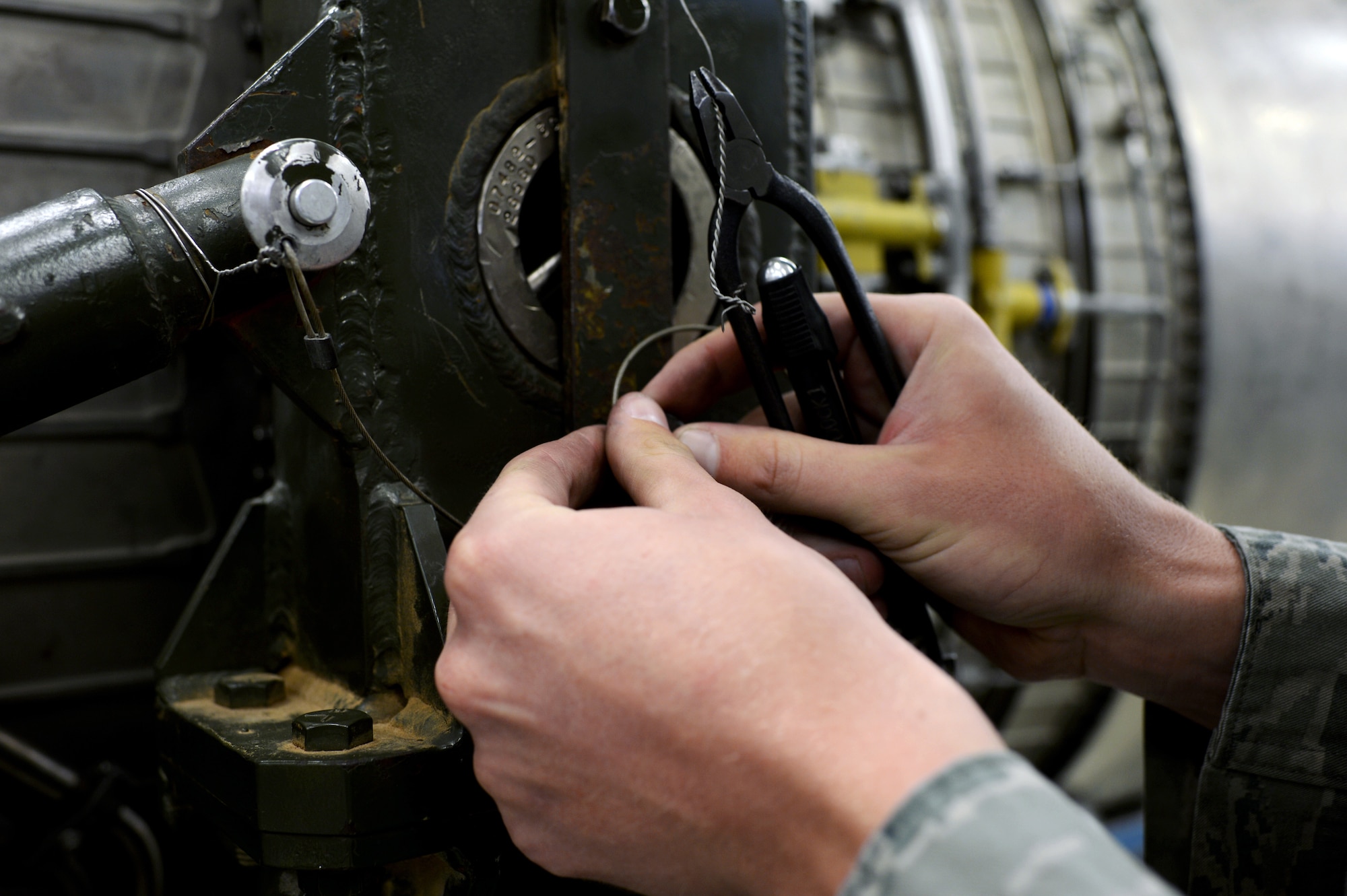 U.S. Air Force Airman 1st Class Ryan Richards, a 52nd Component Maintenance Squadron aerospace propulsion technician from Lake Placid, Fla., tightens a metal wire on a jet engine component in the propulsion shop at Spangdahlem Air Base, Germany, Sept. 9, 2014. The 52nd CMS Airmen practice precision to ensure all mechanical aircraft components function properly. (U.S. Air Force photo by Airman 1st Class Timothy Kim/Released)