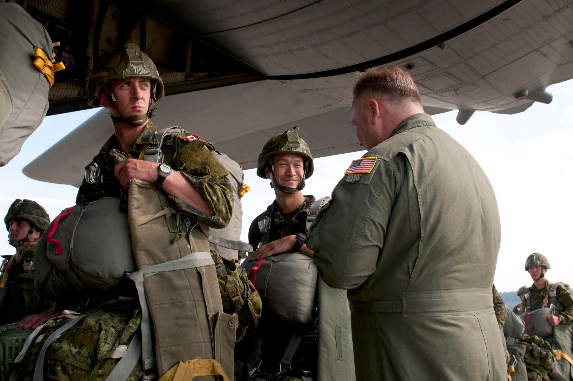 Air Force Master Sgt. Wayne Reeser (right), a loadmaster from the Kentucky Air National Guard’s 123rd Airlift Wing, talks with a paratrooper from the Royal Canadian Regiment at Ramstein Air Base, Germany, just before a Kentucky C-130 Hercules aircraft transports the paratrooper and other NATO forces into the Baltic region Sept. 5, 2014, as part of Operation Sabre Junction. The Kentucky Air National Guard is participating in the operation along with five other Air National Guard Units and forces from 17 NATO countries. (U.S. Air National Guard photo by 2nd Lt. James W. Killen/Released)