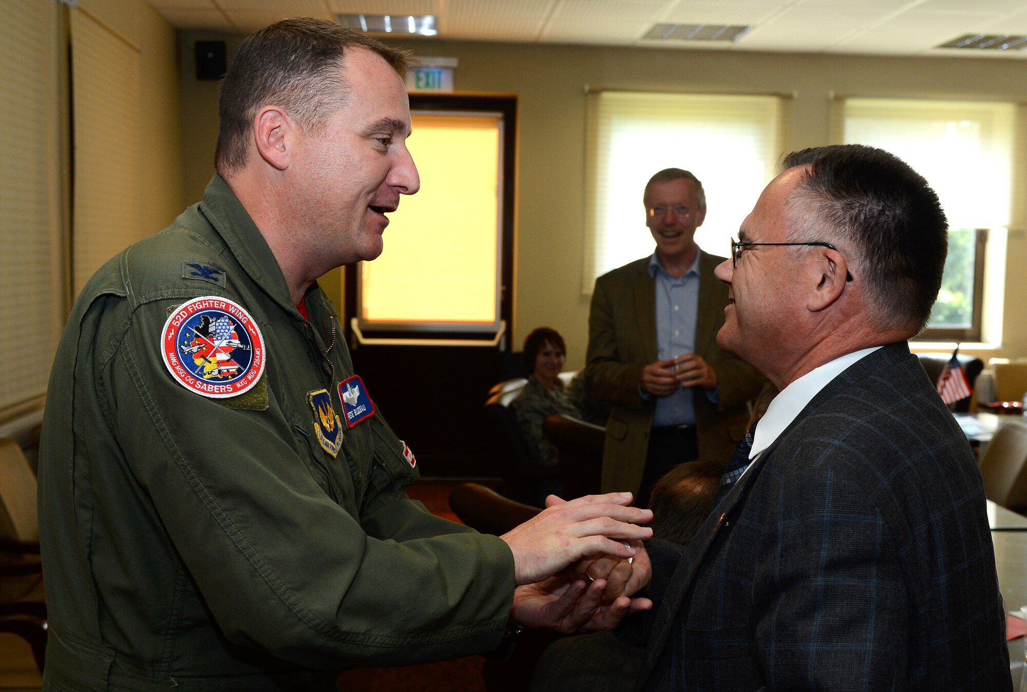 U.S. Air Force Col. Pete Bilodeau, 52nd Fighter Wing commander, congratulates Rudolf Becker, a member of the Host Nation Council Spangdahlem e.V., for his work with the council by coining him before the opening of the HNC desk at the Saber Conference Center at Spangdahlem Air Base, Germany, Sept. 5, 2014. The council has been promoting friendly German-American relations by creating events and opportunities for Sabers since 2003. (U.S. Air Force photo by Airman 1st Class Luke J. Kitterman/Released)