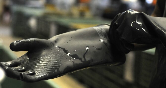 U.S. Air Force Airman 1st Class Myishmial Pearson, 100th Logistics Readiness Squadron Material Management Individual Protective Equipment apprentice from Chicago, puts on protective gloves prior to sanitizing M-50 gas masks Sept. 5, 2014, on RAF Mildenhall, England. Airmen handling liquid chemicals must wear waterproof gloves to protect themselves. (U.S. Air Force photo/Gina Randall/Released)