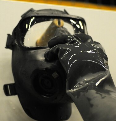 U.S. Air Force Airman 1st Class Myishmial Pearson, 100th Logistics Readiness Squadron Material Management Individual Protective Equipment apprentice from Chicago, hangs a sanitized M-50 gas mask to dry prior to packing Sept. 5, 2014, on RAF Mildenhall, England. The masks are issued to service members prior to deployment. (U.S. Air Force photo/Gina Randall/Released)