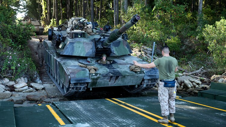 Private 1st Class Nicholas Singler, an M1A1 Abrams tank mechanic for 2nd Tank Battalion, 2nd Marine Division, drives a tank onto an M17 floating raft, while being guided by Cpl. Alexander Tafoya, a combat engineer for Bridge Company, 8th Engineer Support Battalion, 2nd Marine Logistics Group, during a training exercise aboard Marine Corps Base Camp Lejeune, N.C., Sept. 4, 2014. The raft can carry two 70-ton tanks across small bodies of water, while being towed and guided by two Mach 3 Bridge Erection Boats. (U.S. Marine Corps photo taken by Lance Cpl. Alex W. Mitchell/released)
