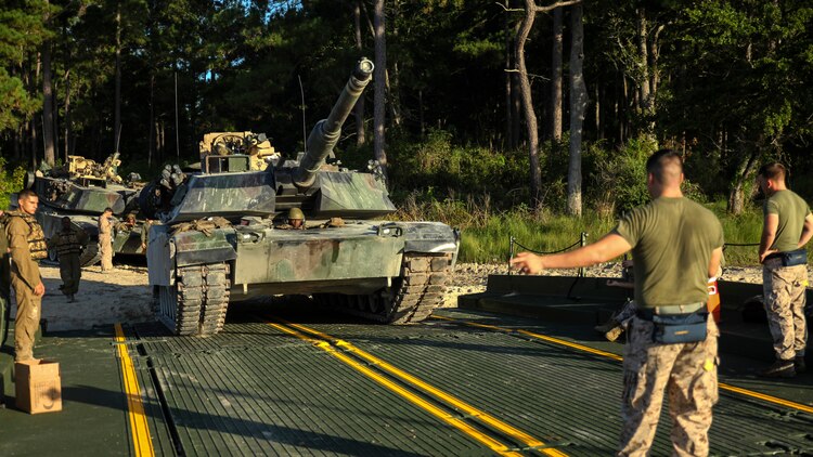 Lance Cpl. Keondre Mitchell, an M1A1 Abrams tank mechanic with 2nd Tank Battalion, 2nd Marine Division, drives a tank onto an M17 floating raft, guided by Cpl. Alexander Tafoya, a combat engineer for Bridge Company, 8th Engineer Support Battalion, 2nd Marine Logistics Group, during a training exercise aboard Marine Corps Base Camp Lejeune, N.C., Sept. 4, 2014. The raft can carry two 70-ton tanks across small bodies of water, while being towed and guided by two Mach 3 Bridge Erection Boats. (U.S. Marine Corps photo taken by Lance Cpl. Alex W. Mitchell/released)