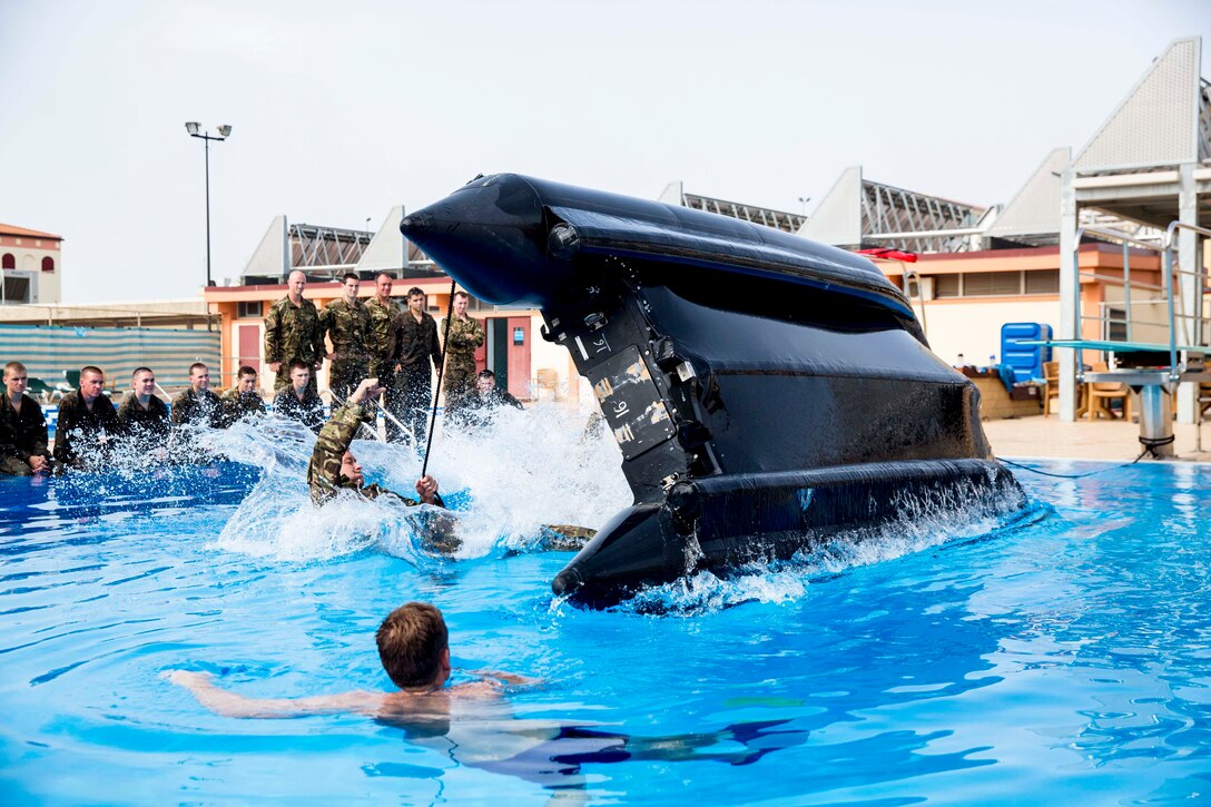 U.S. Marines and British Royal Marines with Special-Purpose Marine Air-Ground Task Force Africa 14 work together to flip a zodiac combat reconnaissance rubber craft during a small-craft capsize exercise aboard Naval Air Station Sigonella, Italy, Aug. 20, 2014. The exercise taught service members how to flip their boat back over safely in the event of a rollover. The drills were used to prepare the service members for upcoming Theater Security Cooperation engagements in Africa where they will be working alongside partner nations and sharing the same techniques. (U.S. Marine Corps photo by Cpl. Shawn Valosin)